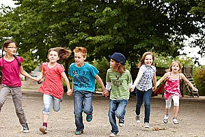 Sechs Kinder, freudig Hand-in-Hand laufend 